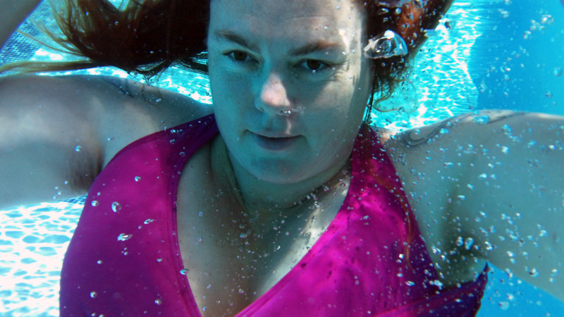 Beth Currans floating in water, a far away look in her dark eyes, arms outstreched